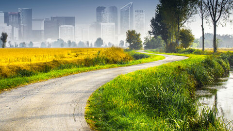 Stadt und Land Feld und Feldweg mit skizzierter Stadt im Hintergrund